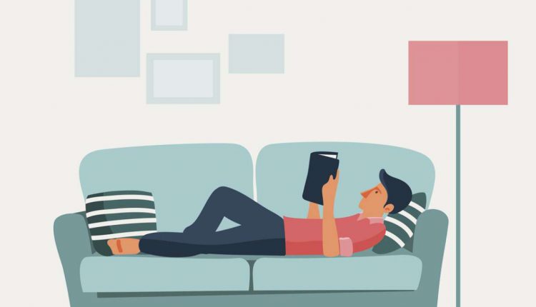 Relaxed young man reading a book on a sofa